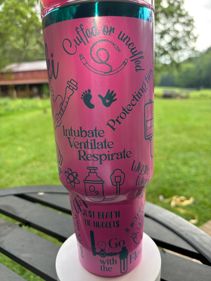 Pink tumbler with medical-themed text and graphics on a table outdoors.